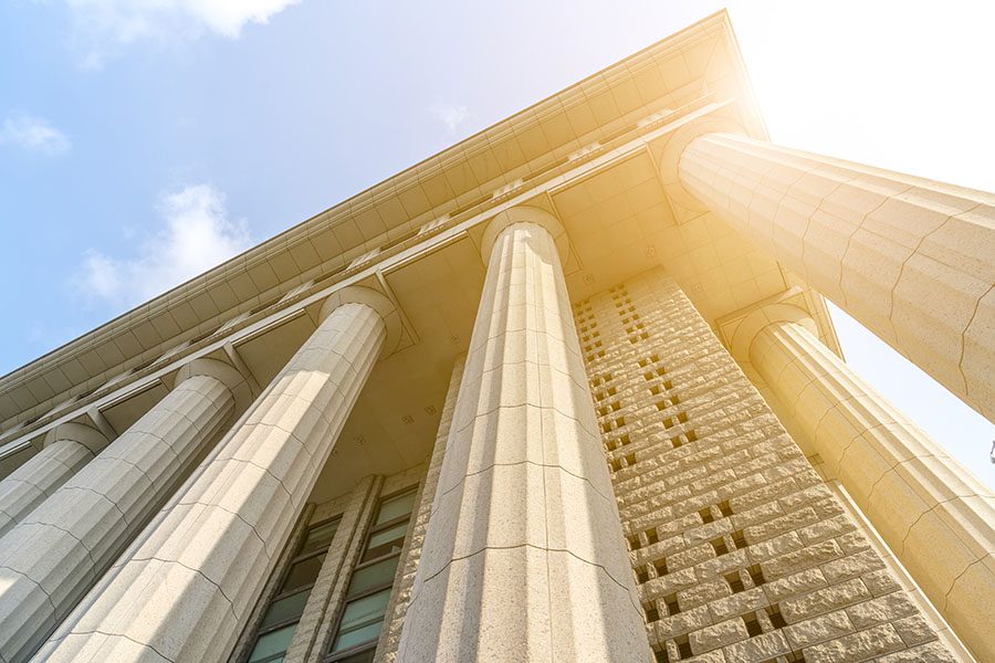 Specialized Business Insurance - Closeup View of Court Building Columns Against Blue Sky